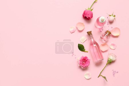 Foto de Botellas de aceite cosmético con extracto de rosa y flores sobre fondo rosa - Imagen libre de derechos
