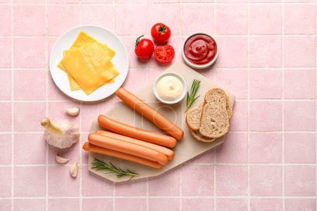 Board of tasty sausages with rosemary and cheese on pink tile background