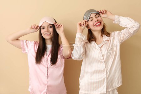 Téléchargez les photos : Amis féminines avec des masques de couchage sur fond beige - en image libre de droit