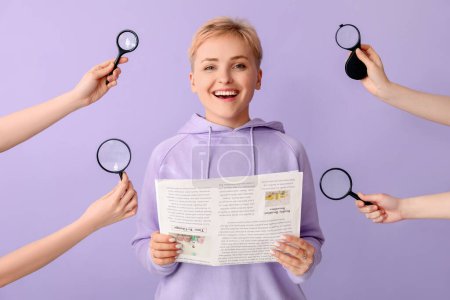 Photo for Young woman holding newspaper and female hands with magnifiers on lilac background - Royalty Free Image