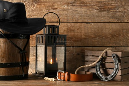 Composición con sombrero de vaquero, cinturón y herradura sobre fondo de madera