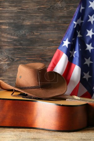 Cowboy hat, guitar and flag of USA on wooden background