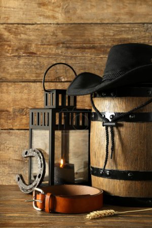 Foto de Composición con sombrero de vaquero, cinturón y herradura sobre fondo de madera - Imagen libre de derechos
