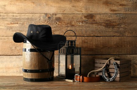 Foto de Composición con sombrero de vaquero, cinturón y herradura sobre fondo de madera - Imagen libre de derechos