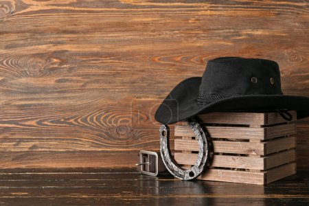 Foto de Sombrero vaquero, herradura y cinturón sobre fondo de madera - Imagen libre de derechos