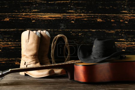 Cowboy hat, guitar and boots on wooden background