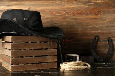 Sombrero vaquero, herradura y lazo sobre fondo de madera