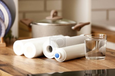 Vaso de agua con filtros en mesa de madera en cocina
