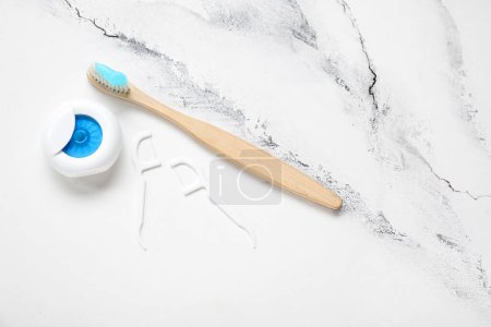 Foto de Hilo dental, mondadientes y cepillo de dientes de bambú sobre fondo de mármol blanco - Imagen libre de derechos