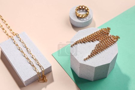 Decorative podiums with golden jewellery on color background