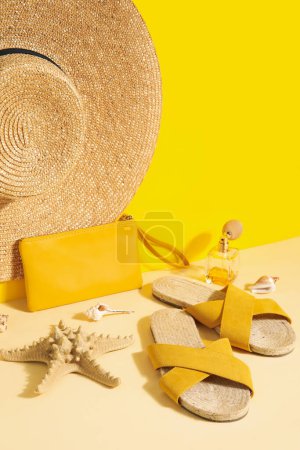 Foto de Sandalias con sombrero de mimbre y perfume cerca de la pared amarilla - Imagen libre de derechos