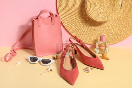 Foto de Par de sandalias de tacón alto con gafas de sol, bolsa y sombrero de mimbre cerca de la pared rosa - Imagen libre de derechos