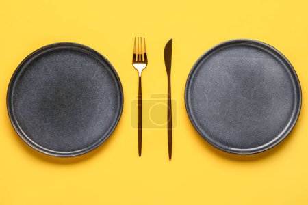 Foto de Ajuste de mesa con platos y cubiertos limpios sobre fondo amarillo - Imagen libre de derechos