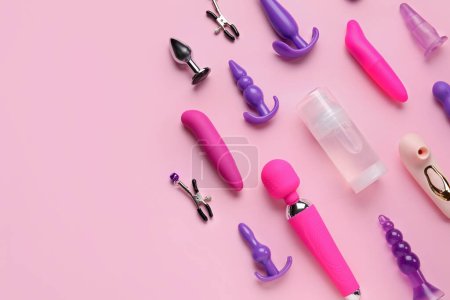 Bottle of lubricant and with vibrators and anal plugs on pink background