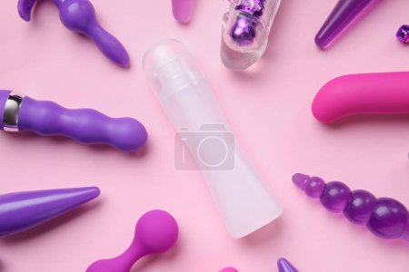 Photo for Bottle of lubricant and with vibrators and anal plugs on pink background - Royalty Free Image