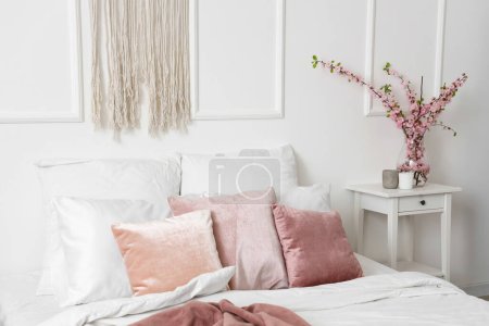 Photo for Interior of cozy bedroom with blooming tree branches in vase - Royalty Free Image