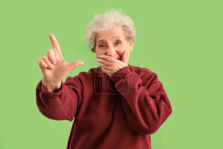 Photo for Senior woman showing loser gesture on green background - Royalty Free Image