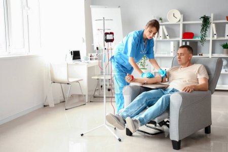 Female nurse taking blood from mature donor in clinic