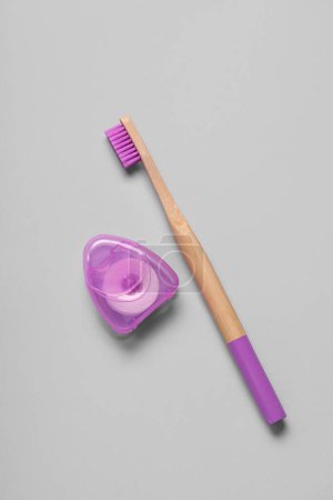 Téléchargez les photos : Fil dentaire et brosse à dents en bambou violet sur fond gris - en image libre de droit