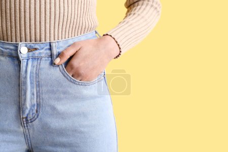 Junge Frau in stylischen Jeans auf gelbem Hintergrund, Nahaufnahme