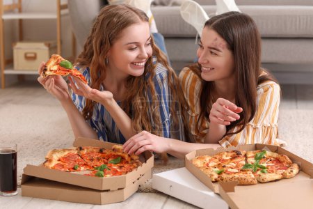 Mujeres jóvenes comiendo sabrosa pizza en casa