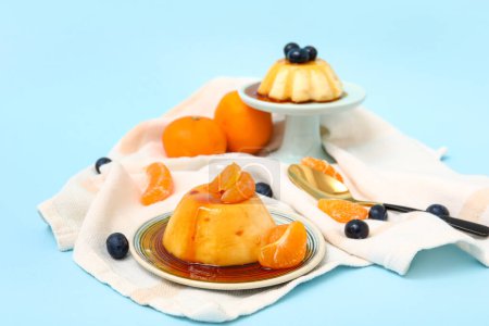 Téléchargez les photos : Délicieux puddings, mandarines et bleuets recouverts de sirop de caramel sur fond bleu - en image libre de droit
