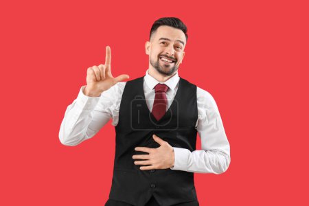 Photo for Handsome man showing loser gesture on red background - Royalty Free Image