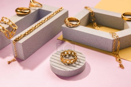 Pedestales de escaparate con anillos y pulseras doradas sobre fondo de color