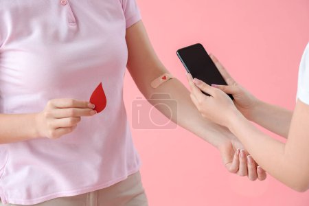 Téléchargez les photos : Jeune femme prenant une photo de donneur de sang sur fond rose, gros plan - en image libre de droit