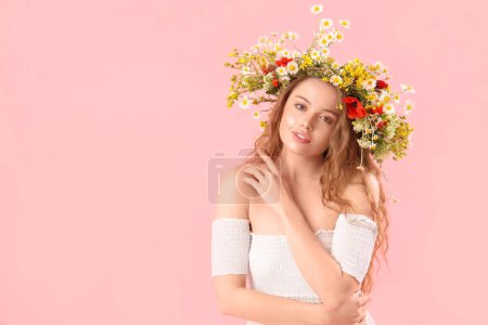 Foto de Hermosa mujer joven en corona de flores sobre fondo rosa. Solsticio de verano - Imagen libre de derechos