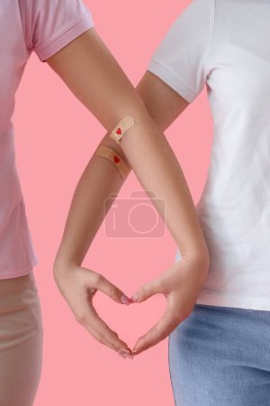Téléchargez les photos : Donneuses de sang femmes faisant coeur avec leurs mains sur fond rose, gros plan - en image libre de droit