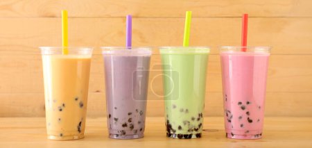 Photo for Plastic cups of different tasty bubble tea on wooden background - Royalty Free Image