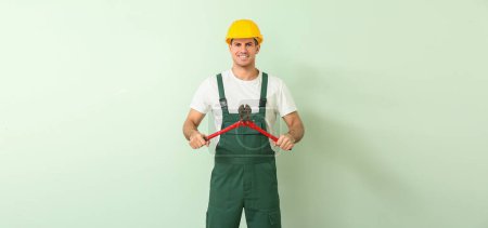 Photo for Handsome male worker with bolt cutter on light green background - Royalty Free Image