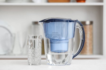 Photo for Water filter jug with glass on table in kitchen - Royalty Free Image