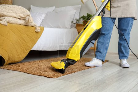 Photo for Housewife hoovering carpet in bedroom - Royalty Free Image