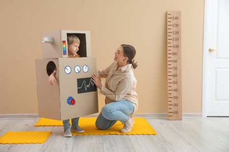 Photo for Little boy in cardboard robot costume with nanny at home - Royalty Free Image