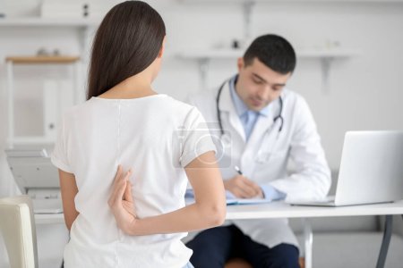 Photo for Young woman with bad posture visiting doctor in clinic, back view - Royalty Free Image
