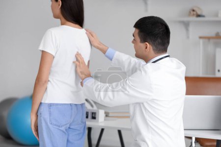 Männlicher Arzt überprüft Haltung junger Frau in Klinik