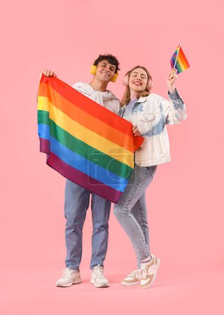 Photo for Young couple in headphones with LGBT flags on pink background - Royalty Free Image