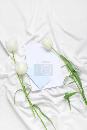 Foto de Tarjetas de invitación en blanco y flores de tulipán en mantel blanco arrugado - Imagen libre de derechos