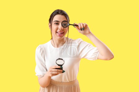 Photo for Young woman with magnifiers on yellow background - Royalty Free Image