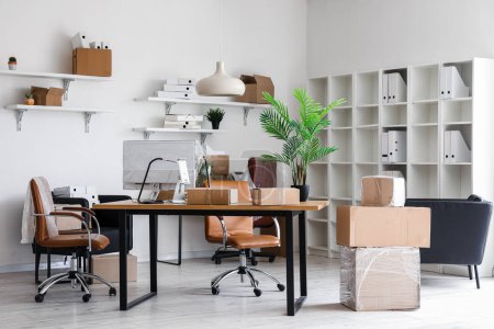 Photo for Interior of office with workplaces and cardboard boxes on moving day - Royalty Free Image