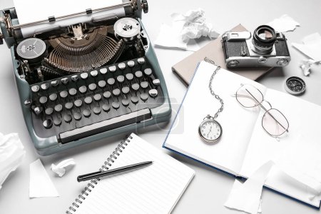 Composition avec machine à écrire vintage, pièces en papier, montre de poche et appareil photo sur fond blanc