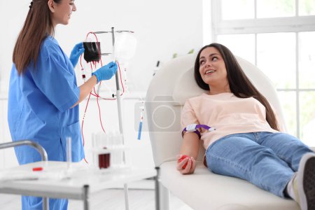 Photo for Female nurse preparing young donor for blood transfusion in clinic - Royalty Free Image