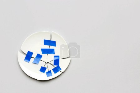 Photo for Broken plate with adhesive tape on light background - Royalty Free Image