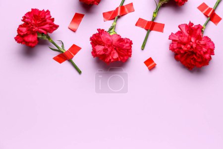Foto de Flores de clavel con cintas adhesivas sobre fondo lila - Imagen libre de derechos