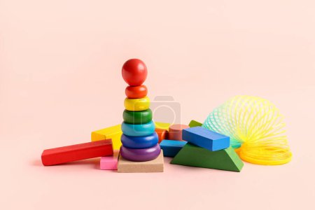 Drewniana kolorowa piramida zabawek z tęczą na różowym tle. Obchody Dnia Dziecka