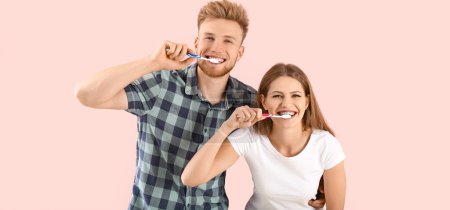 Happy couple brushing teeth on pink background