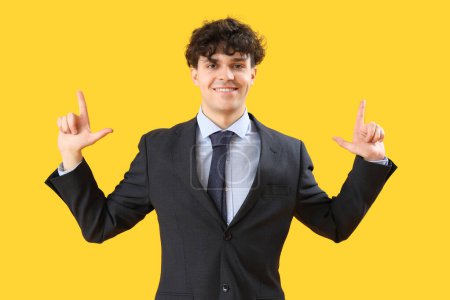 Photo for Young businessman showing loser gesture on yellow background - Royalty Free Image