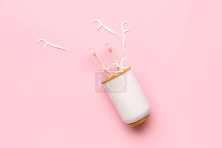 Photo for Overturned toothbrush holder and floss toothpicks on pink background - Royalty Free Image